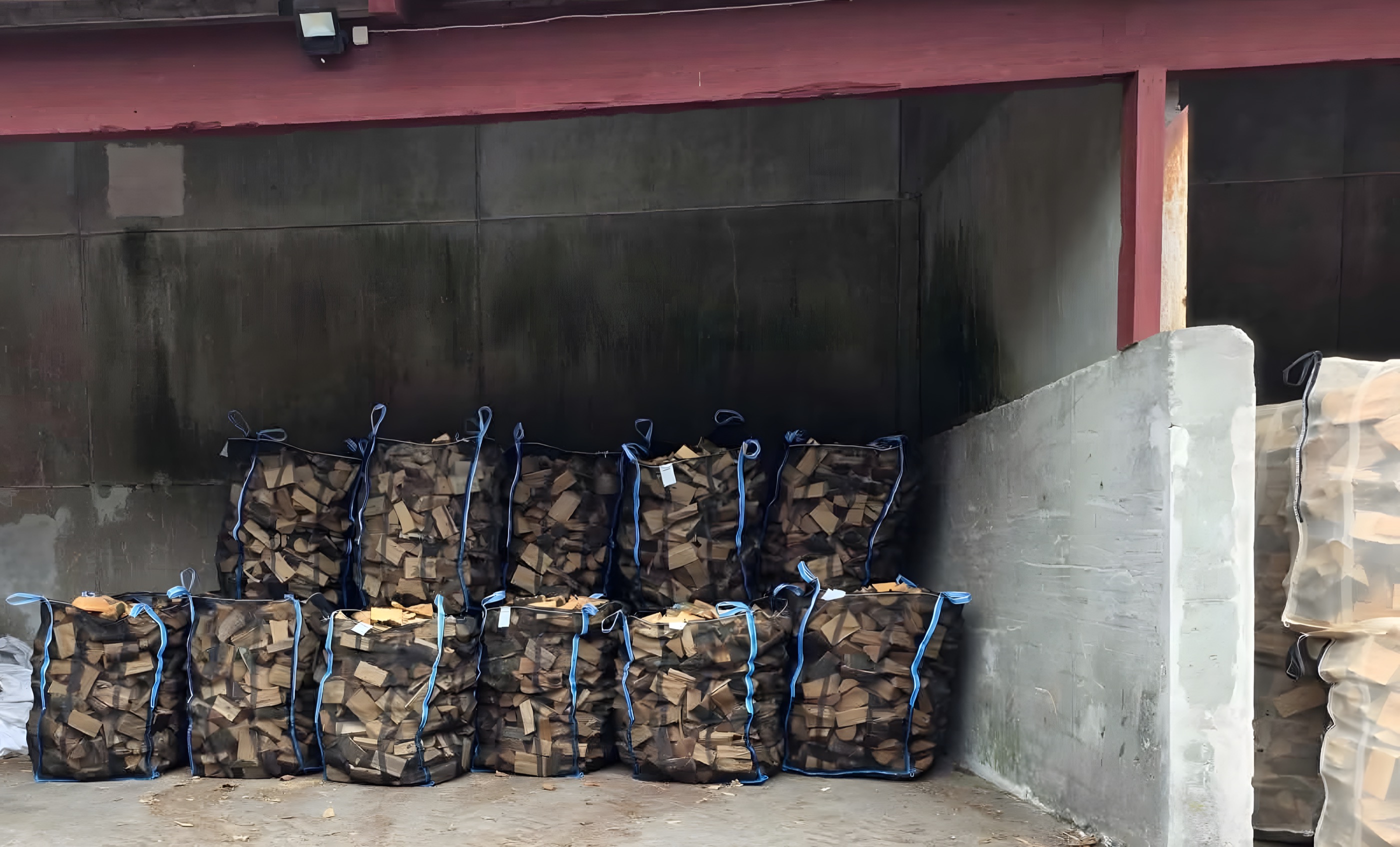 Big bags med brænde opbevaret under halvtag